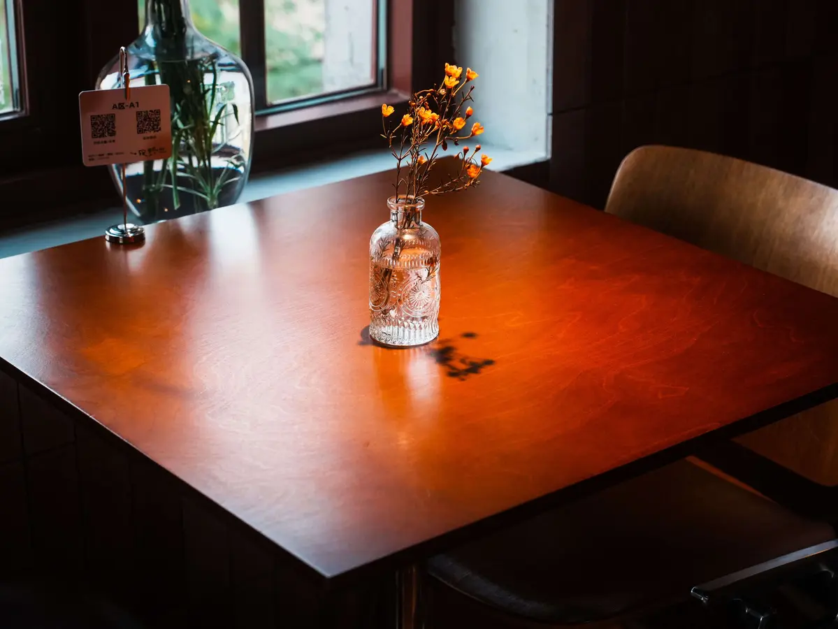 A warmly lit restaurant table by a window, with a QR code menu card in a stand